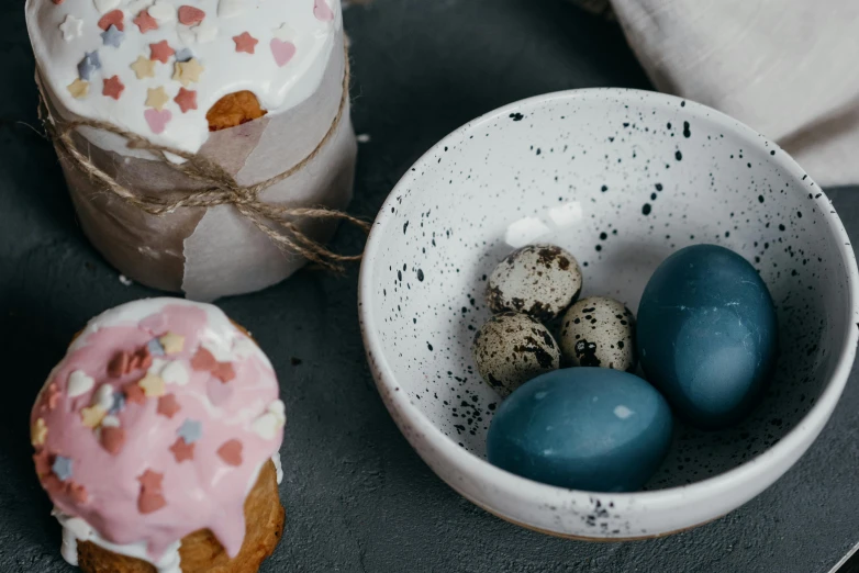 a bowl of eggs and a cupcake with sprinkles, by Emma Andijewska, trending on unsplash, arbeitsrat für kunst, organic ceramic white, varying dots, blue and gray colors, covered with pink marzipan