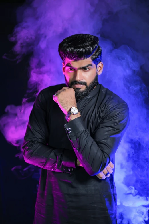 a man standing with his arms crossed in front of smoke, an album cover, inspired by Saurabh Jethani, trending on pexels, fashion model pose, with a beard and a black shirt, bisexual lighting, he is a long boi ”