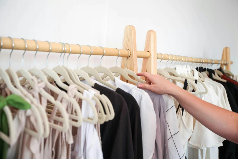 a woman standing in front of a rack of clothes, by Nicolette Macnamara, trending on unsplash, holding a wooden staff, with a white background, close up shots, detailed product image