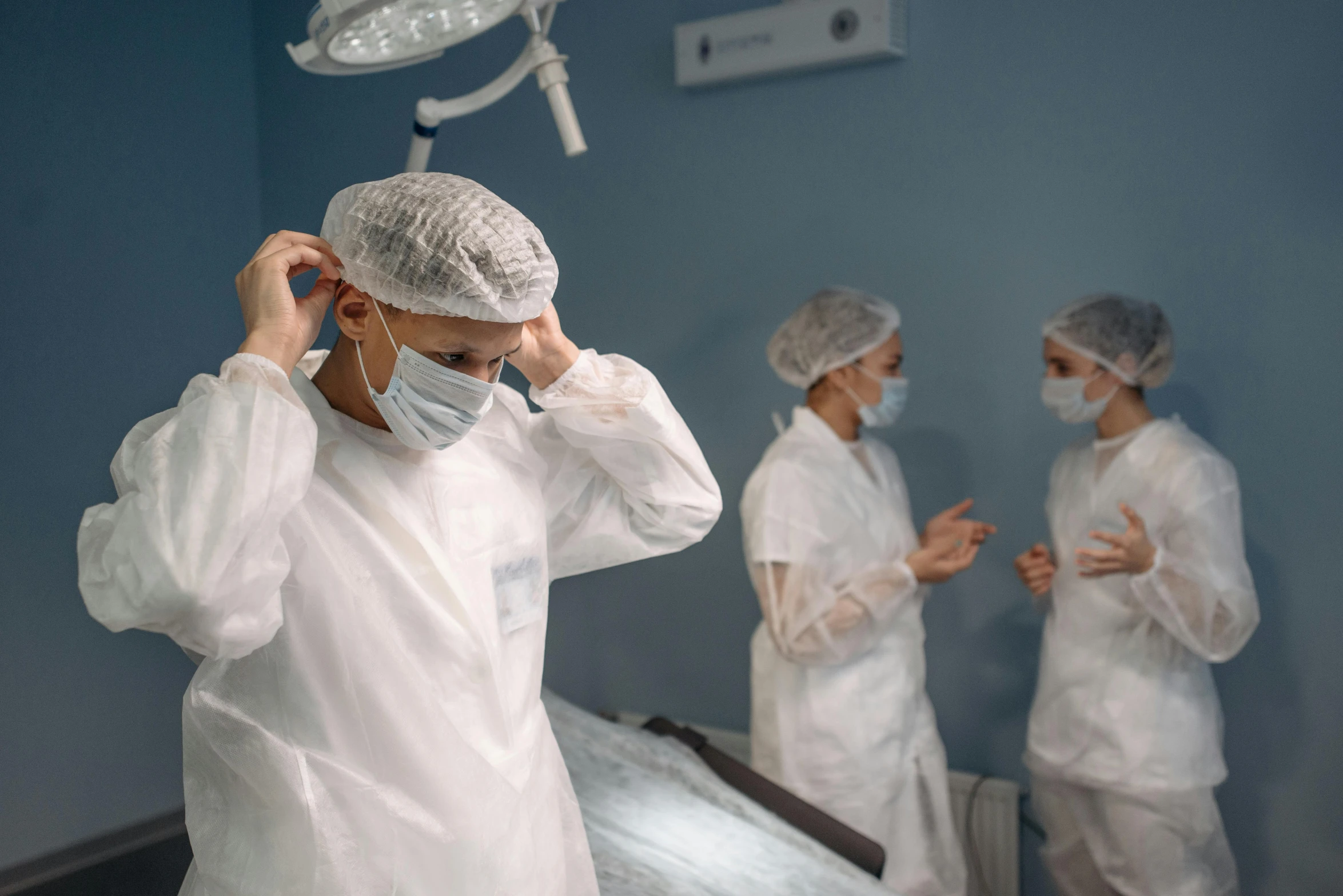 a group of doctors standing next to each other in a room, by Meredith Dillman, pexels contest winner, happening, wearing a white bathing cap, surgical implements, looking tired, avatar image