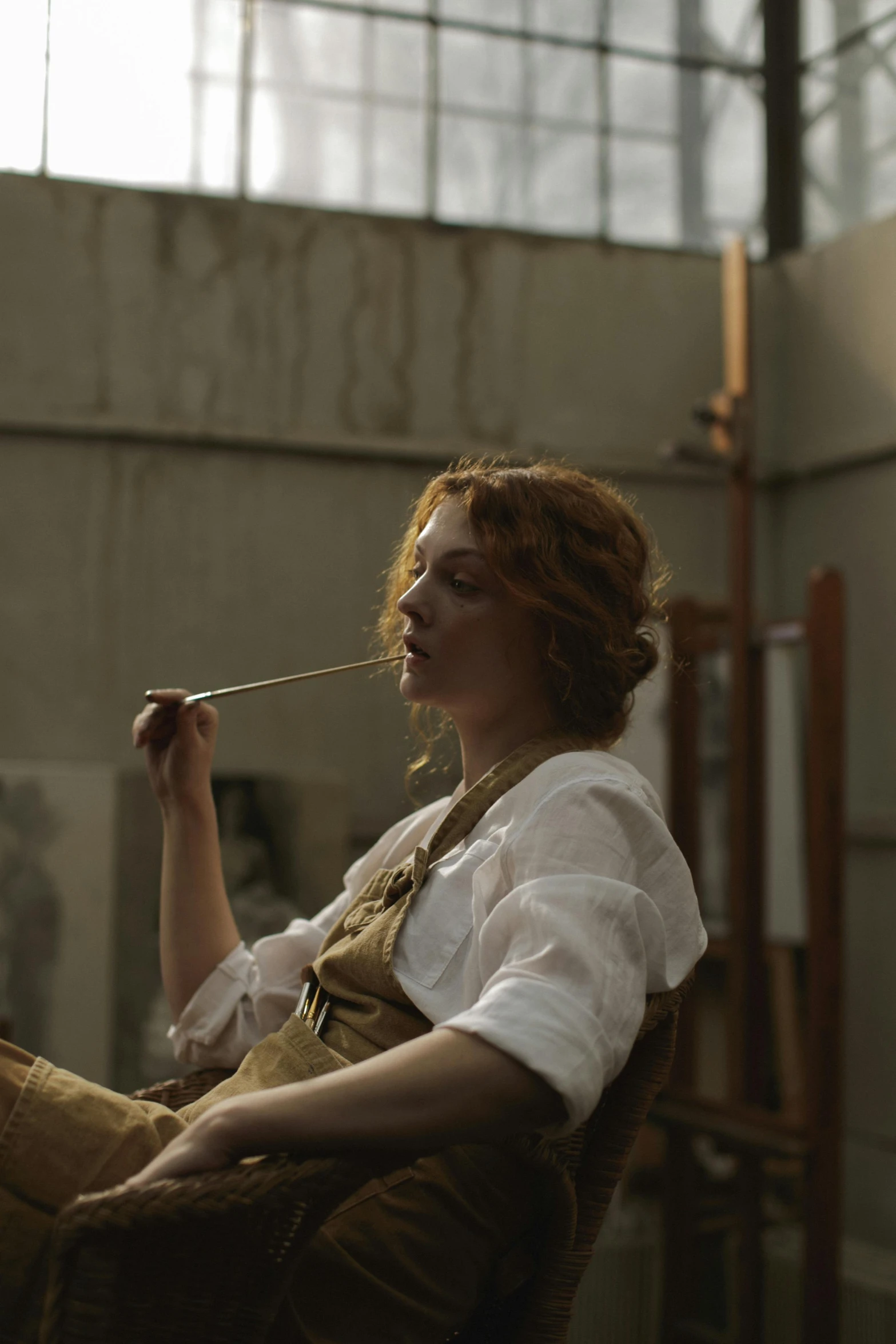 a woman sitting in a chair smoking a cigarette, a photorealistic painting, inspired by Albert Edelfelt, unsplash, australian tonalism, ( redhead, artist wearing overalls, film still from the movie, holding paintbrushes