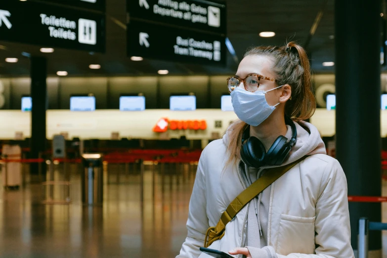 a woman wearing a face mask at an airport, pexels, happening, 🦩🪐🐞👩🏻🦳, avatar image, wearing square glasses, girl wearing headphones