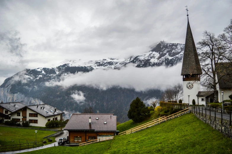 a church sitting on top of a lush green hillside, by Sebastian Spreng, pexels contest winner, chalet, snowy, grey cloudy skies, geiger