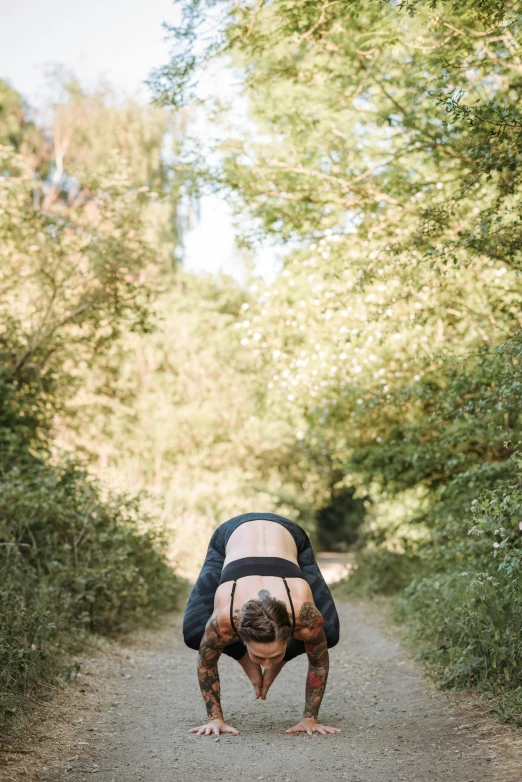 a woman doing a handstand on a dirt road, by Anna Haifisch, unsplash, lying on the woods path, back arched, lotus pose, slightly sunny