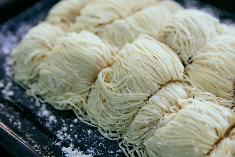 a tray of noodles sitting on top of a table, fluffy neck, detailed entangled fibres, vanilla, piled around