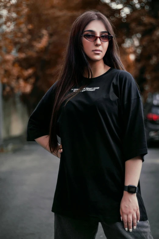 a woman standing in the middle of a street, inspired by Ion Andreescu, pexels contest winner, hurufiyya, wearing a black t-shirt, oversized enginee, black jersey, black car