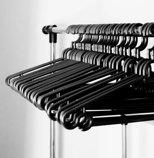 a black and white photo of a rack of clothes, by Kristian Zahrtmann, minimalism, technical detail, mat black metal, collection product, niels otto møller