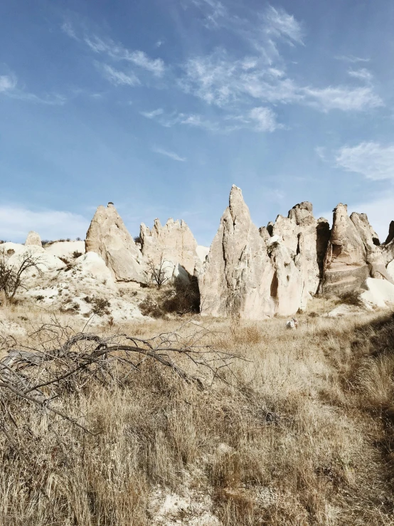 a dirt road running through a dry grass covered field, by Muggur, unsplash, tall stone spires, inside of an expansive cave, panoramic, ((rocks))