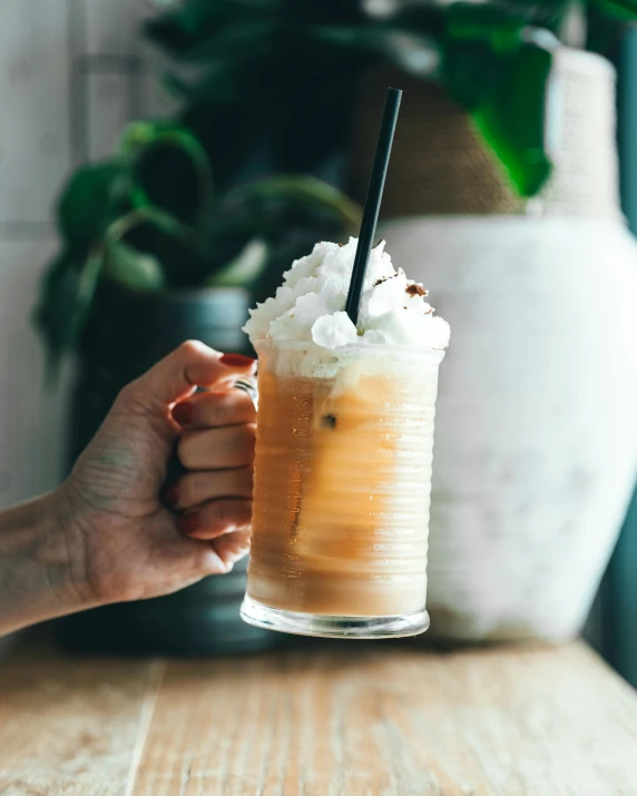 a person holding a glass of iced coffee, by Lucia Peka, trending on unsplash, whipped cream, multiple stories, lgbtq, in a pub