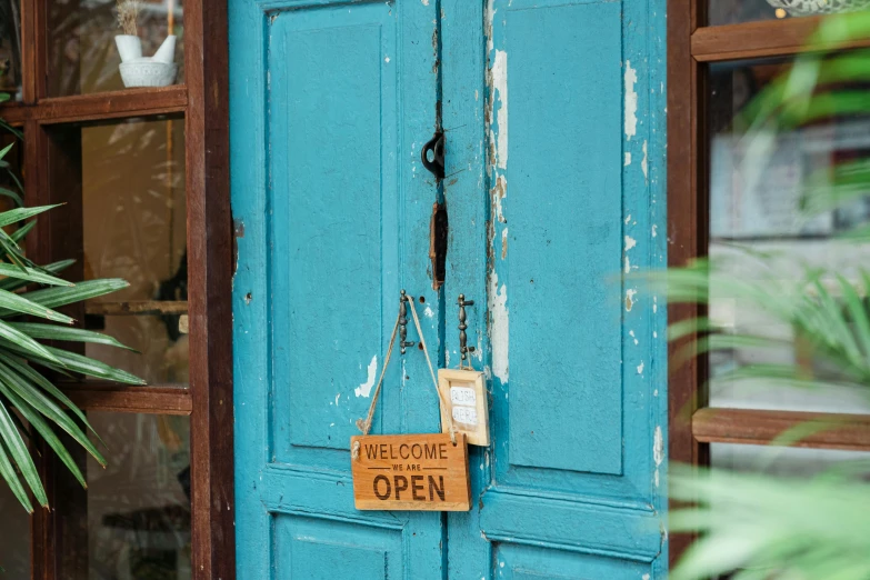 a blue door with a sign hanging on it, by Julian Hatton, trending on unsplash, wooden decoration, upcycled, the store, holding close