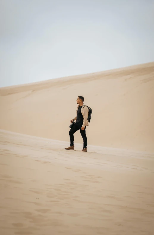 a man standing in the middle of a desert, trending on unsplash, walking over sand dunes, dressed casually, looking left, australian