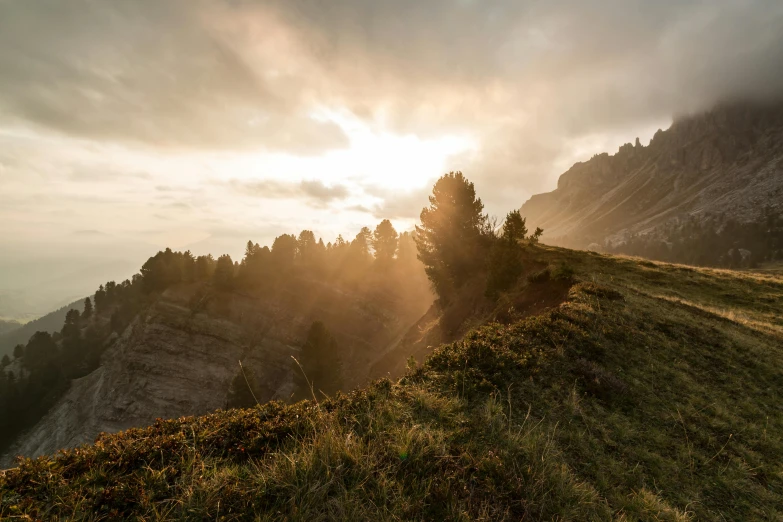 the sun is setting on the top of a mountain, by Sebastian Spreng, unsplash contest winner, romanticism, trees and cliffs, italy, grass spiral mountain landscape, conde nast traveler photo