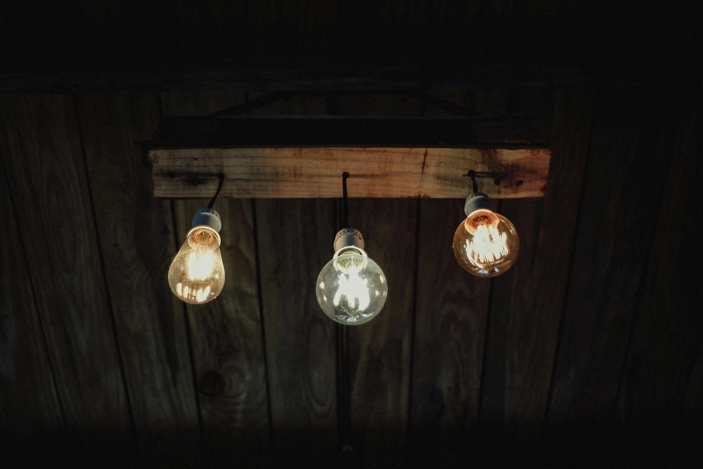 three light bulbs hanging from a wooden ceiling, a portrait, unsplash, good lighted photo