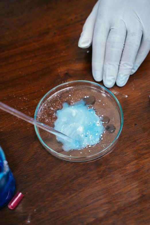 a pair of gloves that are on a table, bubbling liquids, powder, blue crystal exploding, yeast