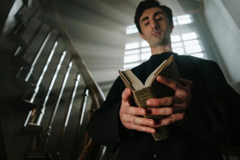 a man holding a book in his hands, by Joseph Severn, pexels contest winner, clear julian lage face, priest, style of nosferatu, colin greenwood (bass)