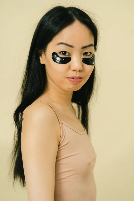 a woman with eye patches on her face, inspired by Tang Di, reddit, photoshoot for skincare brand, made of smooth black goo, facing away from camera, symmetrical eyes and body