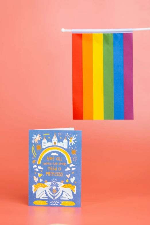 a book sitting on top of a table next to a rainbow flag, greeting card, various items, thumbnail, product shot