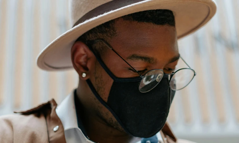 a man wearing a hat, glasses and a face mask, by Austin English, trending on pexels, afrofuturism, dust mask, black stetson hat, with slight stubble, elegantly dressed