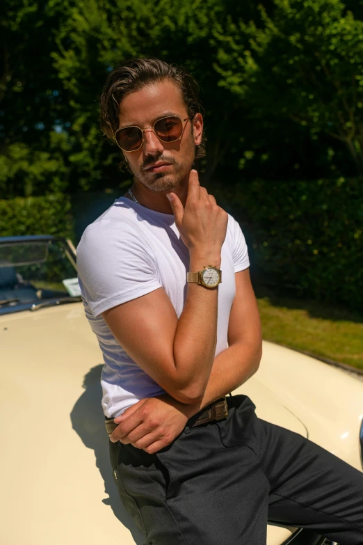 a man sitting on the hood of a car, inspired by Ramon Pichot, pexels contest winner, holding gold watch, fashion model in sunglasses, dressed in a white t shirt, lean man with light tan skin