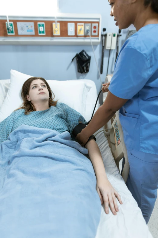 a woman laying in a hospital bed next to a nurse, alexandra daddario, swollen veins, stethoscope, b - roll