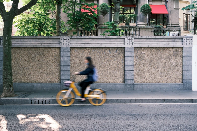 a person riding a bike on a city street, inspired by Cheng Jiasui, pexels contest winner, yellow details, parks and public space, beijing, 🚿🗝📝