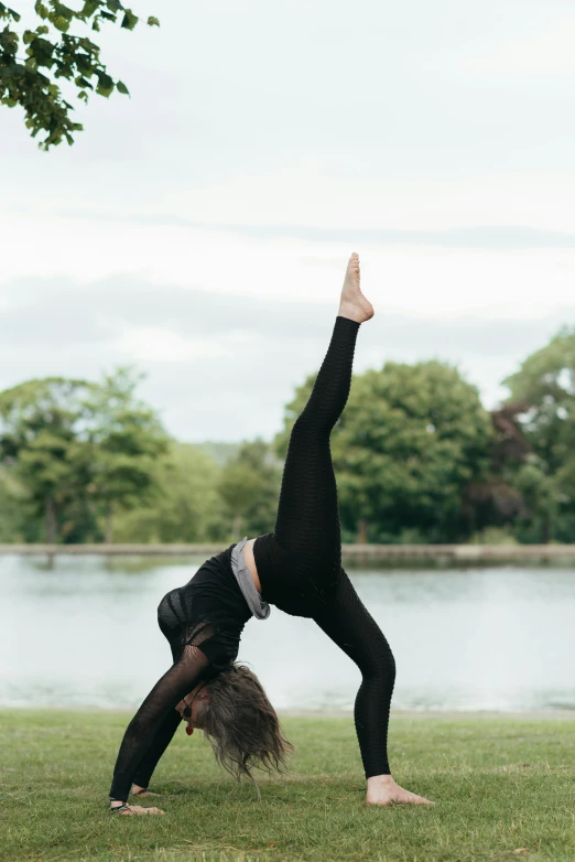 a woman doing a handstand in a park, by Rachel Reckitt, arabesque, on a lake, in an action pose, college, olivia kemp