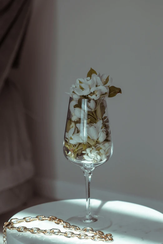 a cake sitting on top of a table next to a wine glass, inspired by Elsa Bleda, unsplash, romanticism, ikebana white flowers, made of drink, close up angle, boudoir