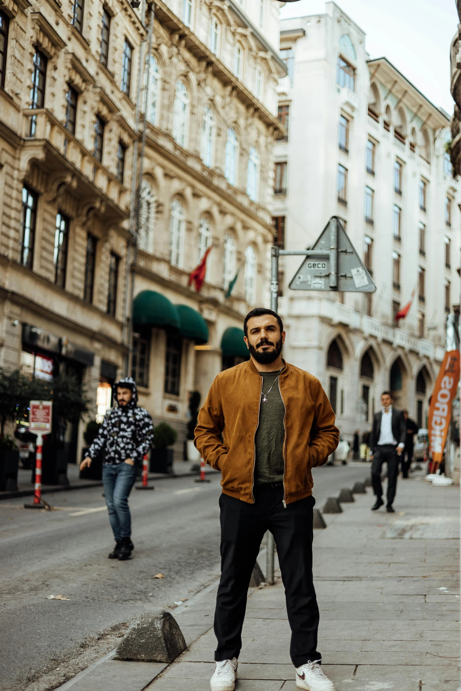 a man standing in the middle of a city street, an album cover, pexels contest winner, renaissance, budapest street background, arab man light beard, 2 people, wearing a bomber jacket