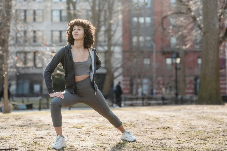 a woman doing a yoga pose in a park, by Nina Hamnett, pexels contest winner, arabesque, wearing a track suit, african american young woman, thumbnail, full body image