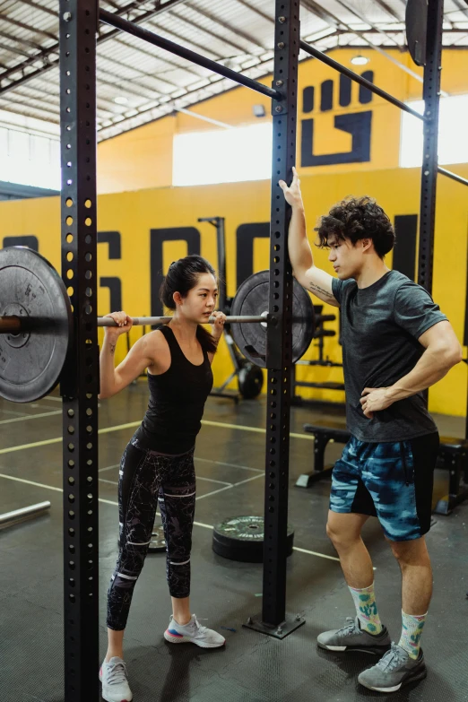 a man and a woman in a crossfit gym, by Robbie Trevino, featured on instagram, black and yellow scheme, kevin hou, profile image, in the high school gym