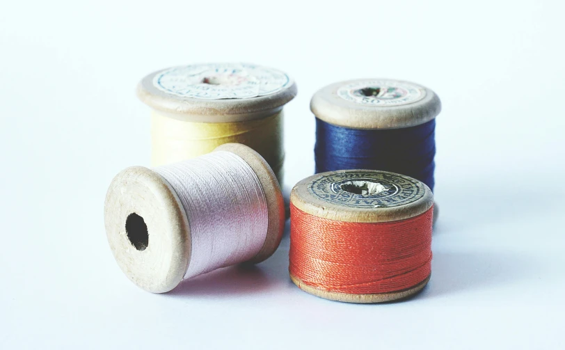 three spools of thread on a white surface, by Sylvia Wishart, unsplash, arts and crafts movement, vintage - w 1 0 2 4, four, set on night, close-up product photo