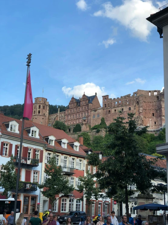 a group of people walking down a street in front of a castle, pexels contest winner, heidelberg school, built on a steep hill, pink, iphone photo, view from across the street