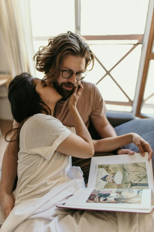 a man and woman sitting on a couch reading a book, a picture, pexels contest winner, visual art, hugging, hipster dad, casually dressed, caucasian