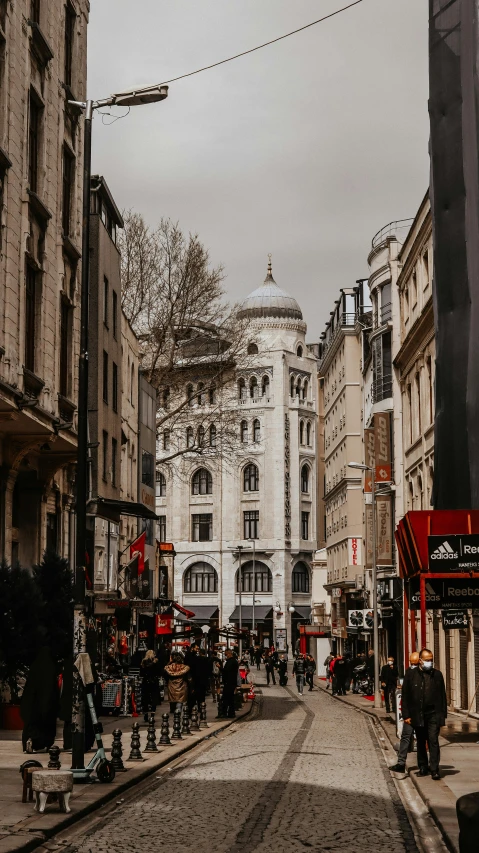 a group of people walking down a street next to tall buildings, by Cafer Bater, pexels contest winner, art nouveau, ottoman empire, grey, neoclassical tower with dome, high resolution photo