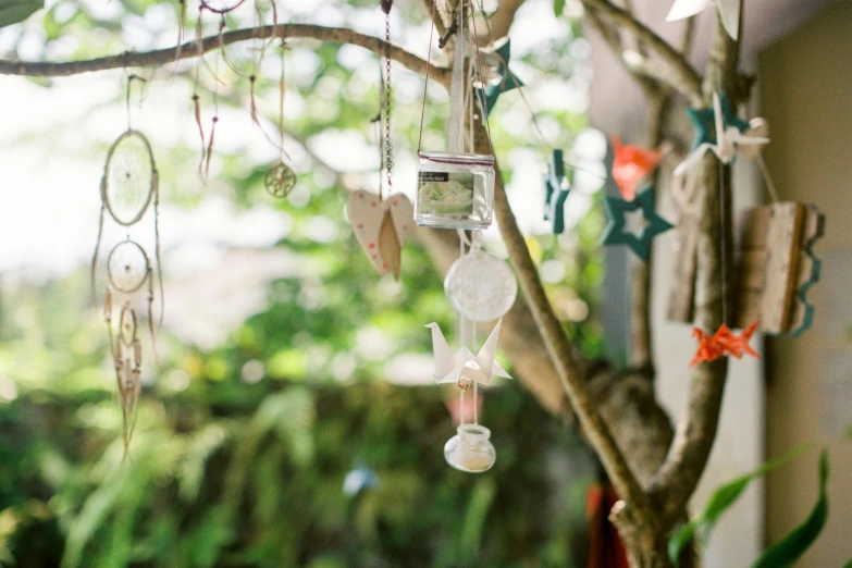 a tree with ornaments hanging from it's branches, a still life, by Jessie Algie, unsplash, visual art, pagoda with a lot of wind chimes, white ceramic shapes, wedding, in the garden