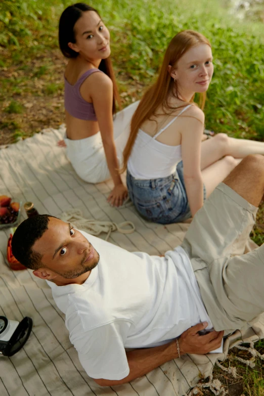 a couple of people sitting on top of a blanket, trending on pexels, renaissance, wearing a vest top, head tilted down, photo of a model, lush surroundings