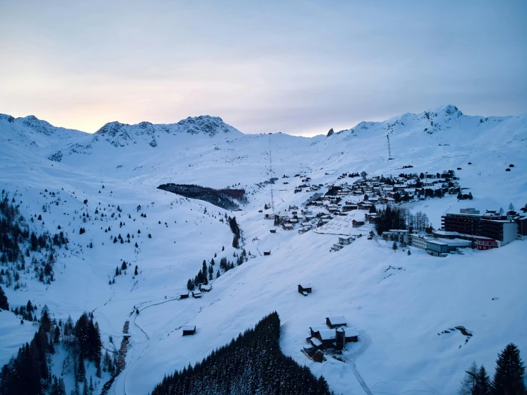 a snow covered mountain with a ski lift in the distance, by Werner Andermatt, pexels contest winner, happening, late evening, wide aerial shot, a cozy, petite
