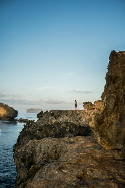 a man standing on top of a cliff next to the ocean, by Simon Marmion, bali, prop rocks, late afternoon, f / 2 0