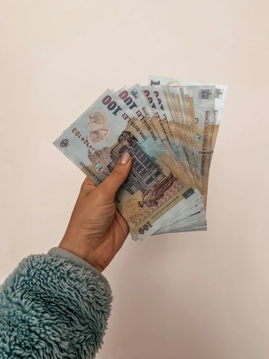 a person holding a bunch of money in their hand, an album cover, by Matija Jama, pexels contest winner, hyperrealism, bahamas, uwu, a cozy, pastel colored