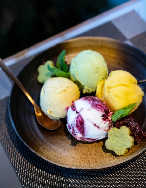 a plate topped with three scoops of ice cream, by Matthias Stom, unsplash, yellow purple green black, mangosteen, ivy's, thumbnail