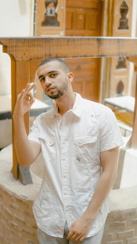 a man in a white shirt talking on a cell phone, an album cover, inspired by Ahmed Yacoubi, pexels contest winner, standing in front of a mirror, casual pose, shaved temple, gif