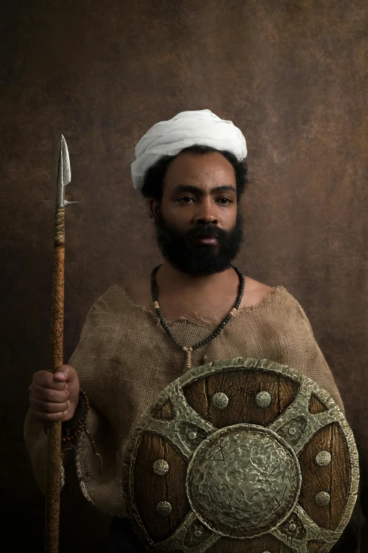 a man in a turban holding a spear and shield, inspired by Osman Hamdi Bey, pexels contest winner, renaissance, black curly beard, an all white human, portrait of modern darna, dwarf