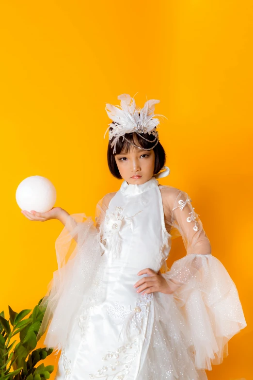 a woman in a white dress holding a ball, an album cover, inspired by Otake Chikuha, rococo, orange halo around her head, studio photo, young asian girl, avant garde supermodel