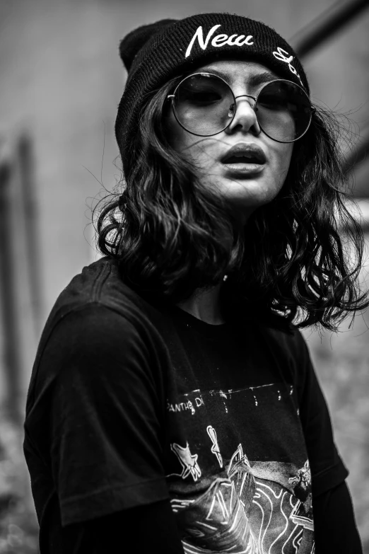 a man with long hair wearing a hat and glasses, a black and white photo, by Lucia Peka, pexels contest winner, charli xcx, wearing a tee shirt and combats, grungy woman, low detailed