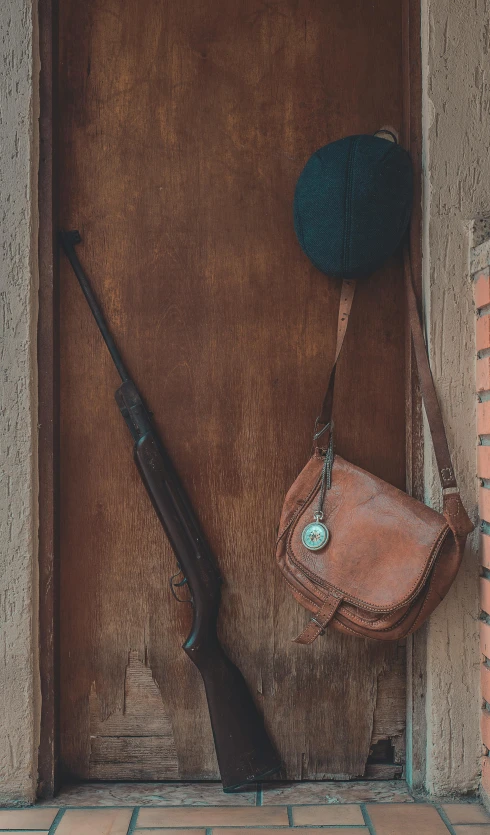 a gun and a hat hanging on a brick wall, a still life, pexels contest winner, leather pouch, 15081959 21121991 01012000 4k, leaning on door, museum quality photo