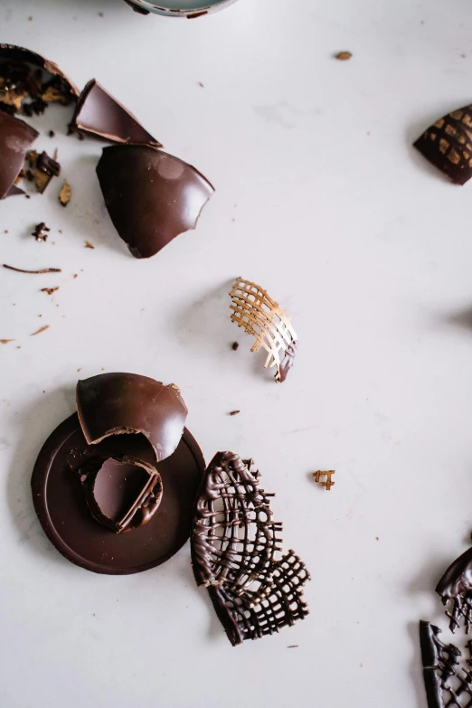 a couple of pieces of chocolate sitting on top of a table, by Jessie Algie, trending on pexels, baroque, grid, broken parts, bells, product shot