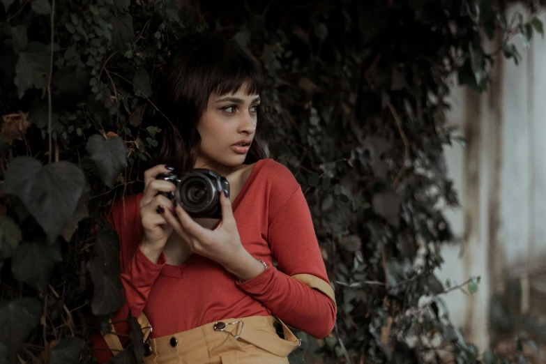 a woman taking a picture with a camera, a picture, inspired by Elsa Bleda, pexels contest winner, wearing a red outfit, isabela moner, amongst foliage, medium format