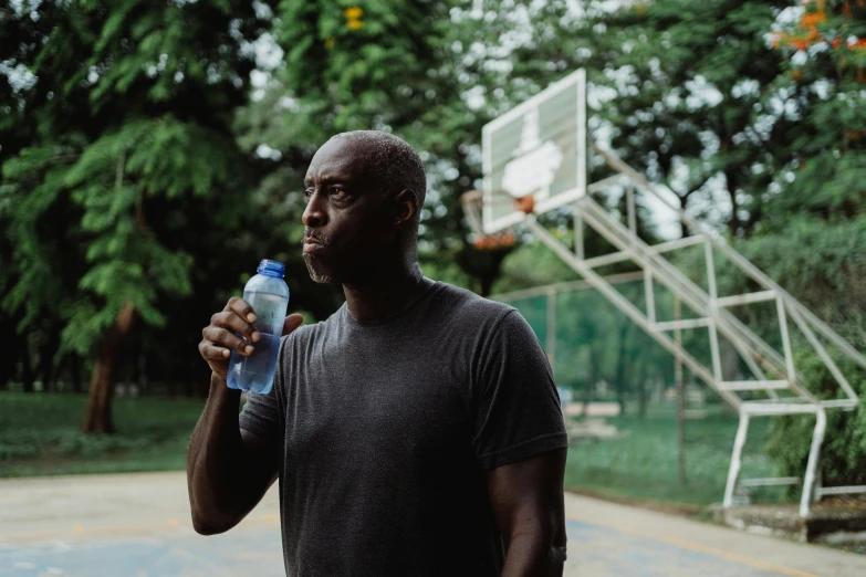 a man standing on a basketball court holding a water bottle, peacefully drinking river water, kevin garnett, profile image, still photography