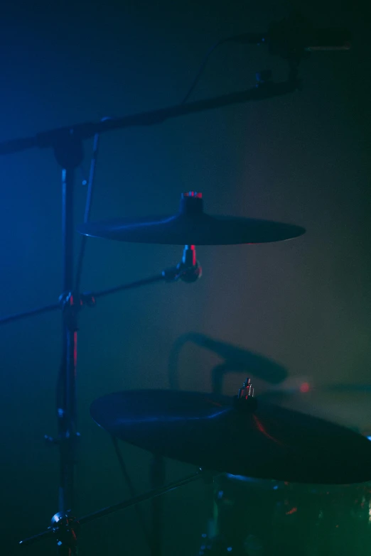 a close up of a drum set on a stage, by David Donaldson, unsplash, experimental studio light, blue and green and red tones, 8 k. volumetric lighting. dark, detail shots