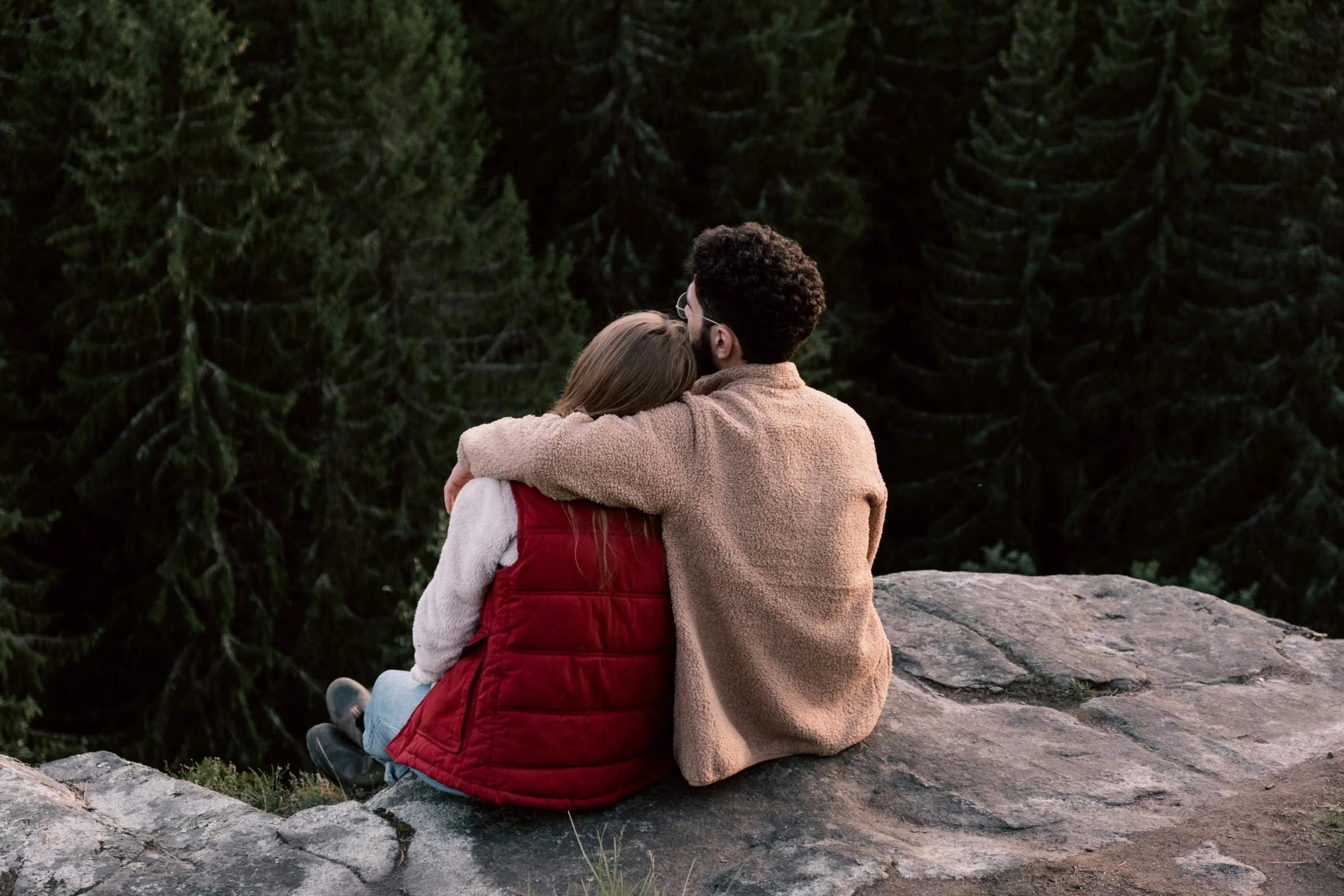 a man and a woman sitting on top of a rock, trending on pexels, romanticism, sweet hugs, cosy, forest picnic, man sitting facing away